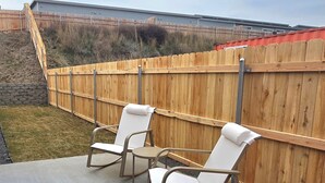 An outdoor patio area with two rocking chairs and a concrete table. - Hill Base Modern (Umatilla)