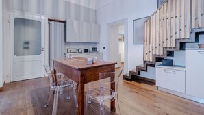 A modern kitchen with a wooden table and chairs, a microwave, and a staircase with wooden steps. - GuestHost - In the heart of Turin, in via Garibaldi, spacious apartment of 100 sqm in an elegant building from 1700. Accommodates up to 5 guests, located on the second floor with an elevator (steps to access it). In the city center, within the pedestrian (Torino)
