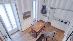 A modern kitchen with a wooden table, clear chairs, a hanging light fixture, and a built-in oven. - GuestHost - In the heart of Turin, in via Garibaldi, spacious apartment of 100 sqm in an elegant building from 1700. Accommodates up to 5 guests, located on the second floor with an elevator (steps to access it). In the city center, within the pedestrian (Torino)