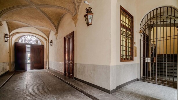 A hallway with arched ceilings, a wooden door, and a barred gate. - GuestHost - In the heart of Turin, in via Garibaldi, spacious apartment of 100 sqm in an elegant building from 1700. Accommodates up to 5 guests, located on the second floor with an elevator (steps to access it). In the city center, within the pedestrian (Torino)