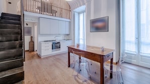 A modern kitchen with white cabinets, a wooden dining table, and a staircase. - GuestHost - In the heart of Turin, in via Garibaldi, spacious apartment of 100 sqm in an elegant building from 1700. Accommodates up to 5 guests, located on the second floor with an elevator (steps to access it). In the city center, within the pedestrian (Torino)