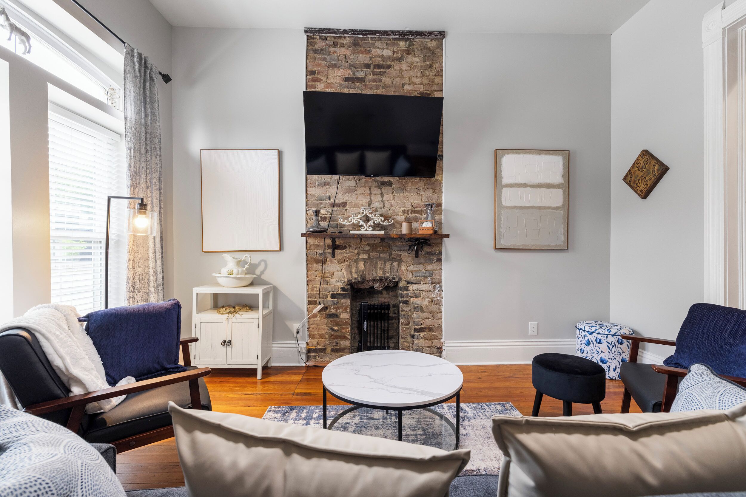 A living room with a fireplace, a flat-screen TV mounted above it, and a comfortable seating area with a round coffee table.