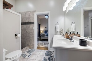 A bathroom with a toilet, sink, and shower area.