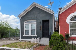 A two-story house with a black front door, a white-framed window, and a small porch with steps.