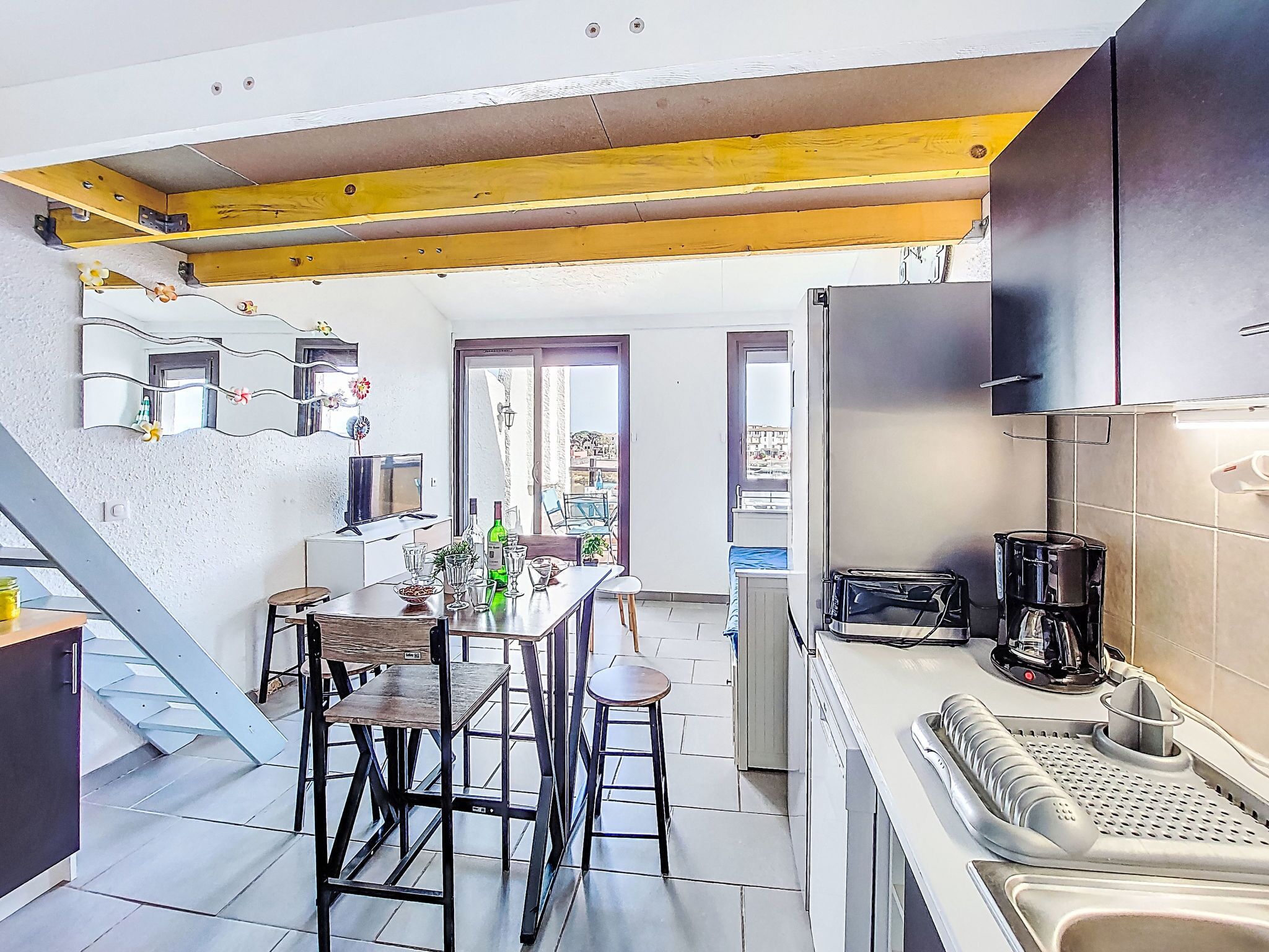 Une cuisine moderne avec un coin repas, une machine à café et une vue sur l’extérieur.