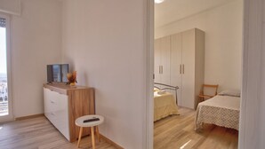 Um quarto com uma cama, mesa de cabeceira, uma cadeira e um guarda-roupa.