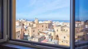 Vista pela janela de um horizonte urbano com edifícios e céu claro.
