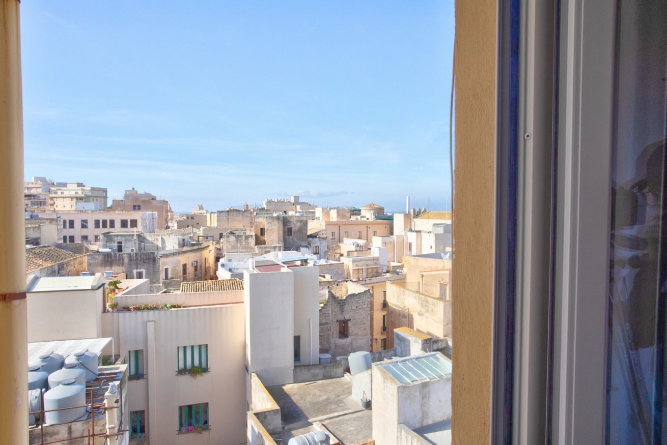 A view of a cityscape through a window, featuring multiple buildings with varying architectural styles and rooftops.