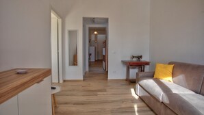 Uma sala de estar moderna com piso de madeira, um sofá com almofada amarela e uma mesa pequena.