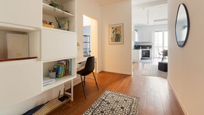 Un intérieur moderne avec un bureau, une chaise, une bibliothèque et, au fond, une cuisine.