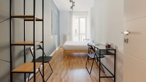 Une chambre moderne équipée d’un lit, d’un bureau, de chaises et d’étagères intégrées.
