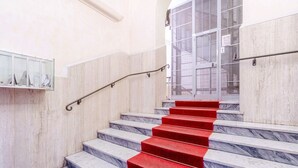 A marble staircase with red carpeted steps and metal handrails. - GuestHost - In the heart of Genoa, on Via Rivoli, a cozy 60 sqm apartment ideal for 3 guests. Located on the -1 floor of a building without an elevator, it offers comfort and tranquility just steps from the lively city center. The area is well served by  (Genova)
