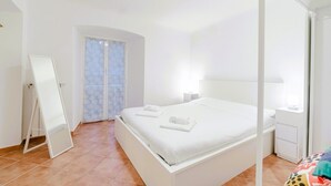 A bedroom with a bed, a nightstand, a mirror, and a wardrobe. - GuestHost - In the heart of Genoa, on Via Rivoli, a cozy 60 sqm apartment ideal for 3 guests. Located on the -1 floor of a building without an elevator, it offers comfort and tranquility just steps from the lively city center. The area is well served by  (Genova)
