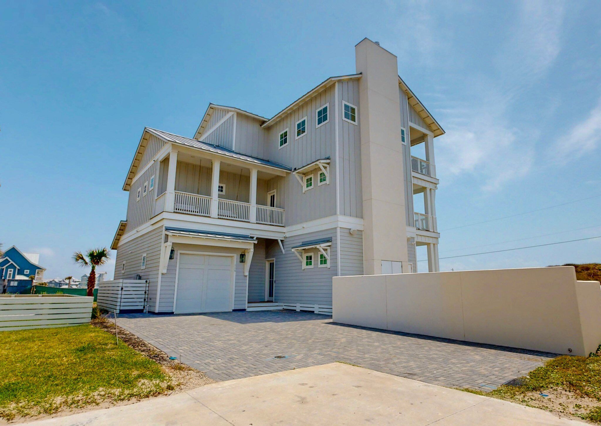 A two-story residential building with a balcony on the second floor, a garage, and a paved driveway.