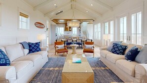 A spacious living room with a high ceiling, a central coffee table, and two sofas with patterned cushions. - SBT115 Private Pool, Pickleball Court, Sauna, Boardwalk to the Beach (Port Aransas)