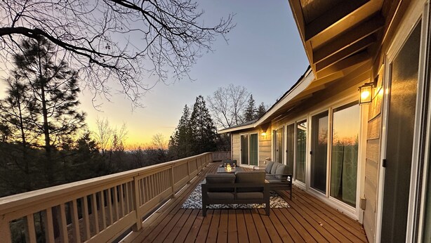 A wooden deck with outdoor seating and large windows.