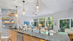 Una cocina moderna con una isla grande, luces colgantes y vistas al exterior.