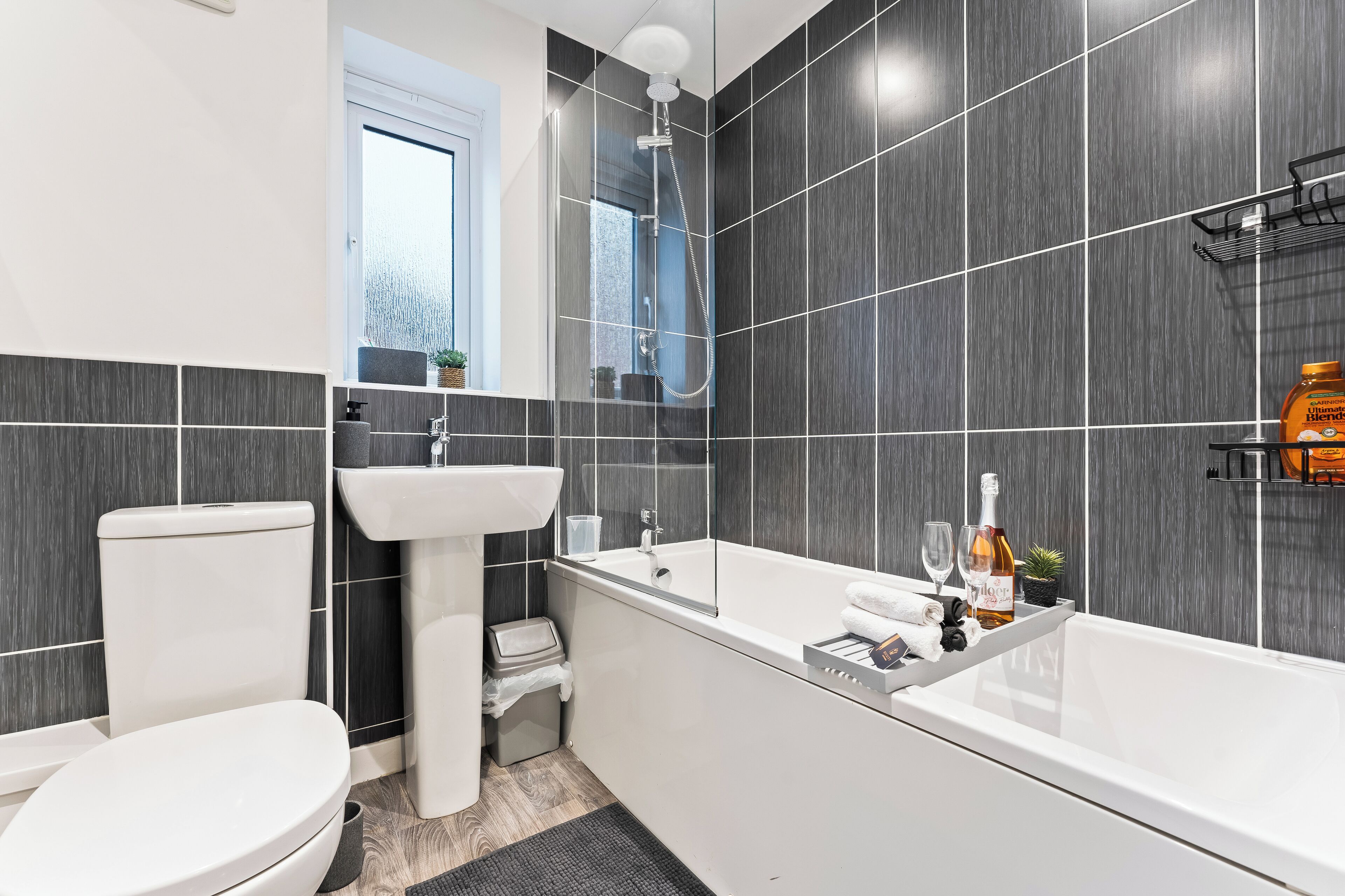 A modern bathroom with a toilet, sink, bathtub, and shower.