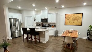 Una cocina moderna con armarios blancos, electrodomésticos de acero inoxidable y una mesa de comedor de madera.