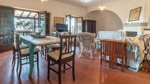 A dining area with a wooden table and chairs, a television, and a fireplace.