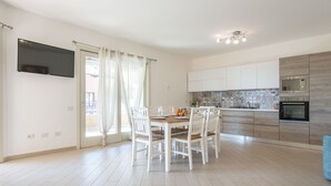 A modern kitchen with white cabinets, a built-in oven, and a microwave.