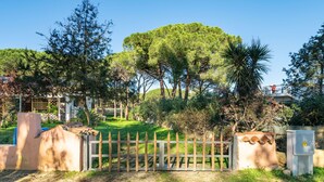 A gated entrance to a property with a paved driveway, surrounded by trees and greenery. - Vacation home Itaca by Interhome (Villasimius)