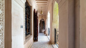 A corridor with patterned flooring, ornate doorways, and a hanging light fixture. - Palais Nejma (Marrakech)