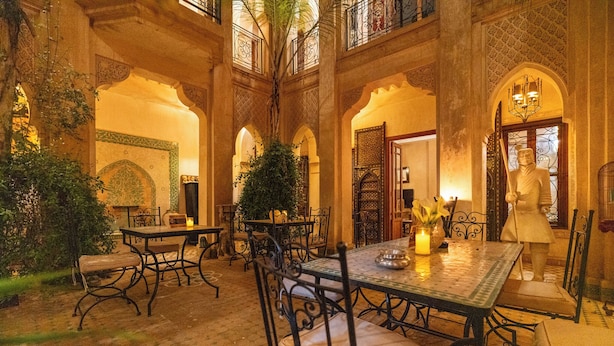 A courtyard with a central table and chairs, surrounded by arches and a statue. - Palais Nejma (Marrakech)
