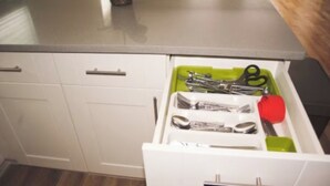 A kitchen drawer with utensils and a green tray. - Harrel Vacation Rentals (Omaha)