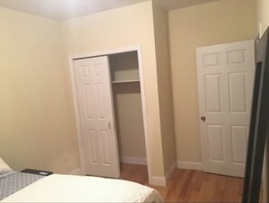 A bedroom with a bed, a closed door, and a partially open closet. - Harrel Vacation Rentals (Omaha)