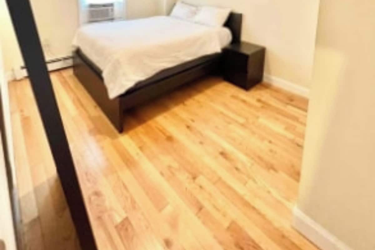 A bedroom with a bed, a nightstand, and a window.