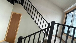 Eine Treppe mit schwarzen Geländern und einer geometrischen Deckenleuchte.
