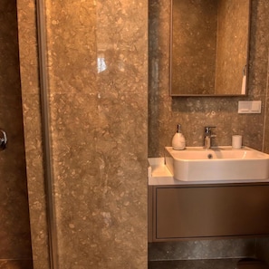 A bathroom with a marble wall, a sink, a mirror, and a towel rack. - Cunda Taka (Ayvalik)