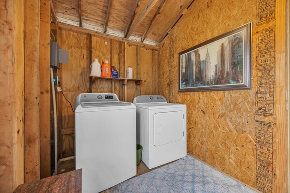 Una sala de lavandería con dos lavadoras y un estante con productos de limpieza.