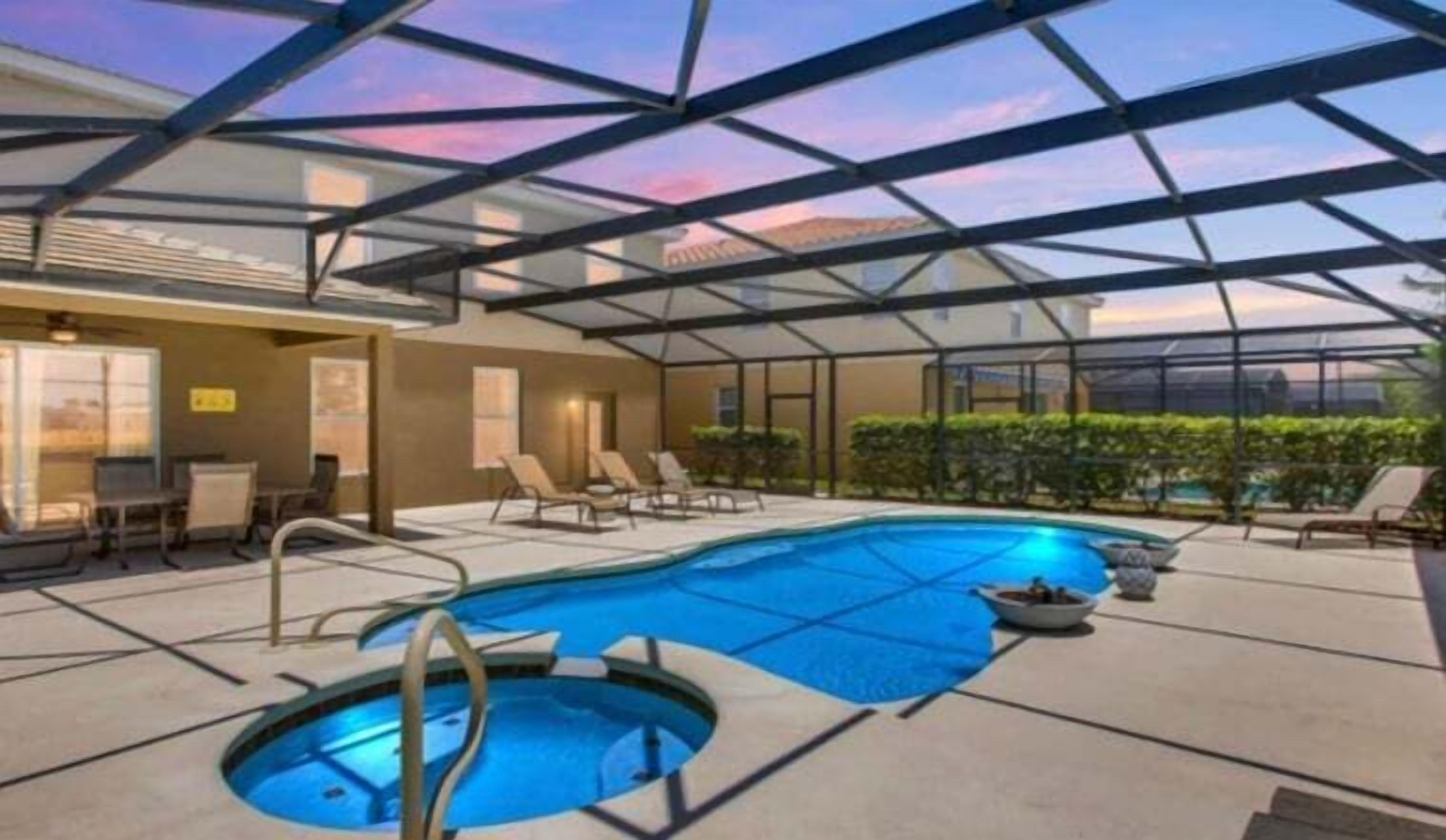 A modern indoor pool area with a glass ceiling, lounge chairs, and a small pool.