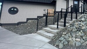 A two-story building with a stone facade, a metal roof, and a staircase leading to the entrance.