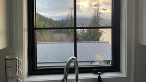 Un baño con ventana que ofrece vistas a un bosque y montañas.