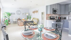 A modern kitchen with grey cabinets, a microwave, and a stove. There is a dining area with a glass table set for four, surrounded by chairs. - Sunnyvale 3B2b Super Big House (Sunnyvale)