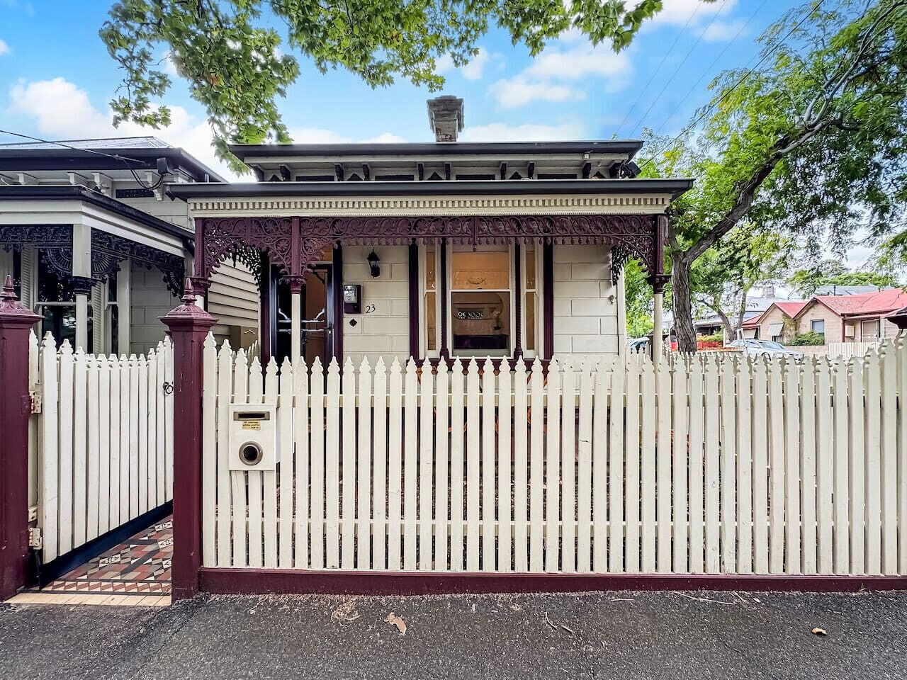 A house with a white picket fence, a porch with intricate woodwork, and a mailbox.