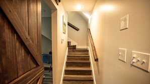 Eine Holztreppe mit Handlauf, Lichtschalter und Steckdose an der Wand.