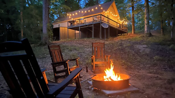 Eine Hütte mit einer Terrasse, Sitzgelegenheiten im Freien und einer Feuerstelle.