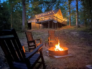 A cabin with a deck, outdoor seating, and a fire pit.