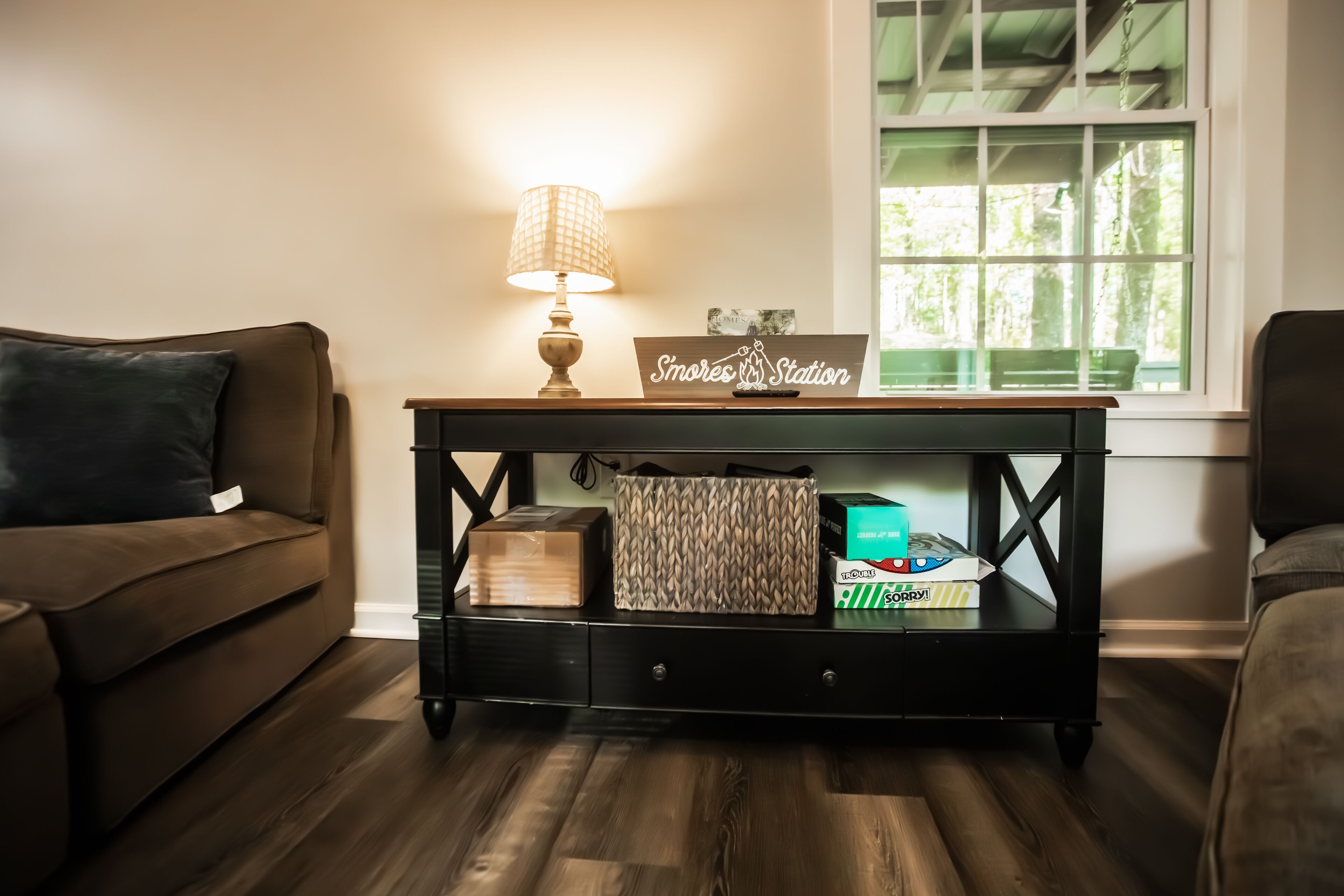 Un salon chaleureux avec un canapé marron, une table basse en bois sur laquelle est posée une lampe, et une pancarte indiquant « Poste de ronflement ».