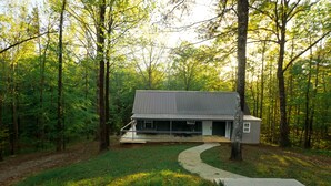 Eine Holzhütte mit überdachter Veranda, umgeben von einem Wald.
