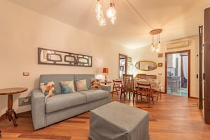 Een woonkamer met een bank, salontafel, eettafel, stoelen en hanglampen.
