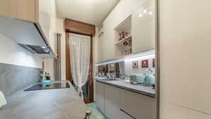 A modern kitchen with a marble countertop, stainless steel appliances, and a decorative curtain. - 5' from Bocconi University with 2 Bedr and 2 Bathr (Milano)