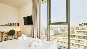 Habitación de hotel con una cama grande, un escritorio con silla, televisión de pantalla plana y vistas a la ciudad.