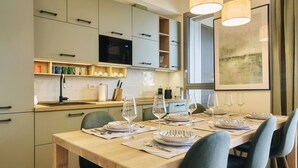 Una cocina moderna con armarios de colores claros, microondas y un comedor para cuatro con una mesa y sillas de madera.
