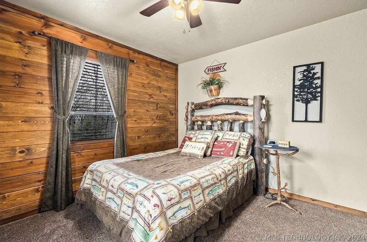 A bedroom with a wooden wall, a bed with a fish-themed bedspread, a small table with a 'happy' sign, and a 'FISHIN' sign on the wall.