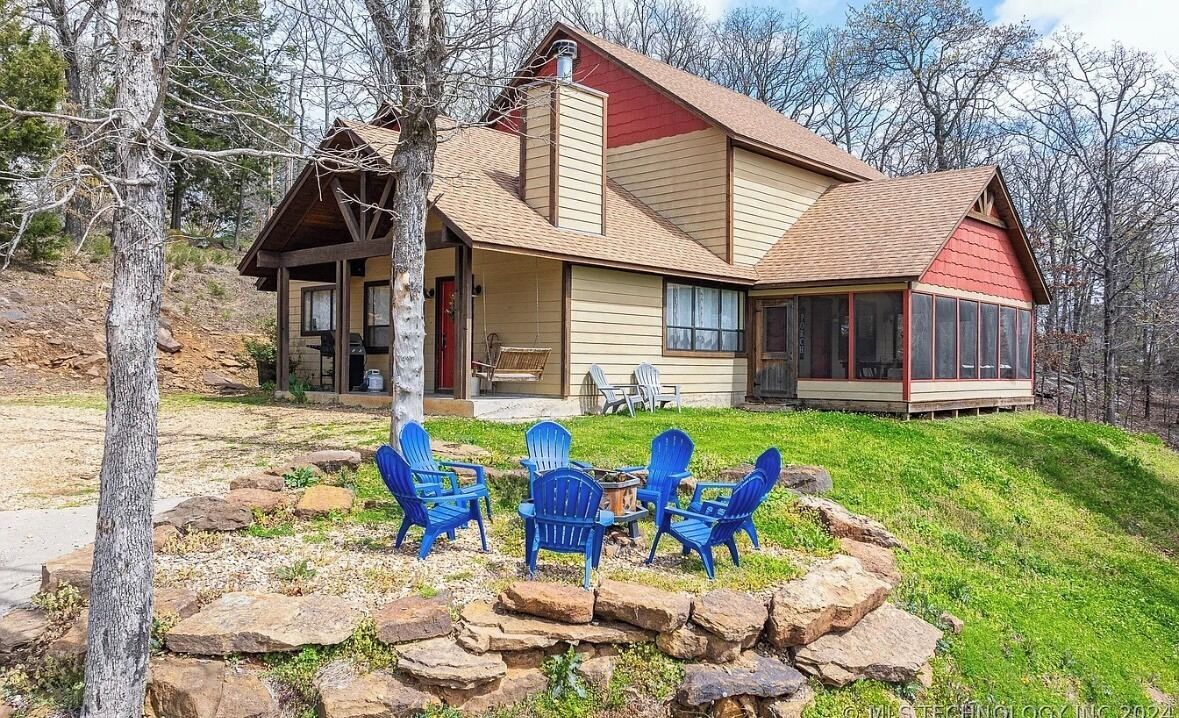 A lodge with a covered porch, outdoor seating, and a stone fire pit.